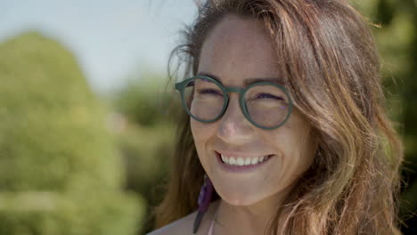 Close-Up-Of-Beautiful-Happy-Young-Woman-With-Glasses-Smiling,-Drinking-And-Talking-With-Friends