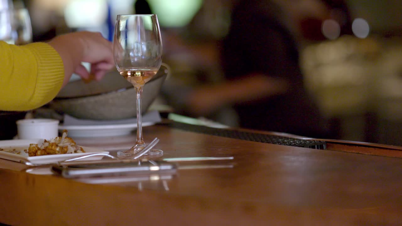 Shows a close-up shot of a rustic wooden table in a Vermont restaurant, featuring a plate, a glass of wine, with a cozy, dimly lit ambiance in the background.