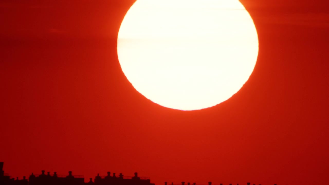 近代的な都市のスカイラインを照らす、輝く黄金の夕焼け。