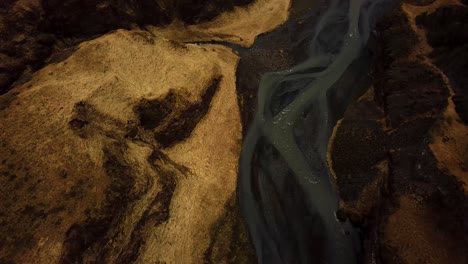 aerial view of a river flowing through iceland highlands on volcanic black sand
