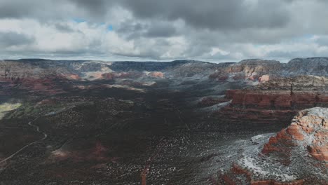 snow capped red rock mountains against overcast sky in sedona, arizona - aerial drone shot