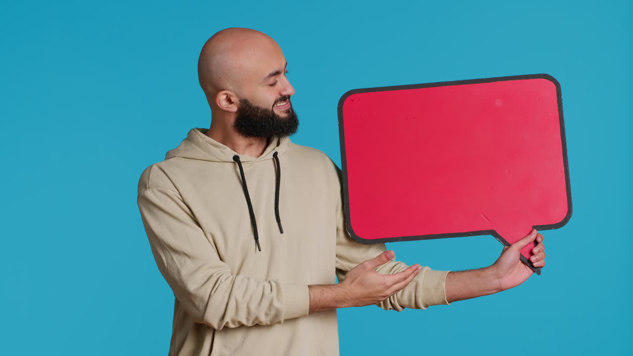 Arab person holding red speech bubble icon in studio