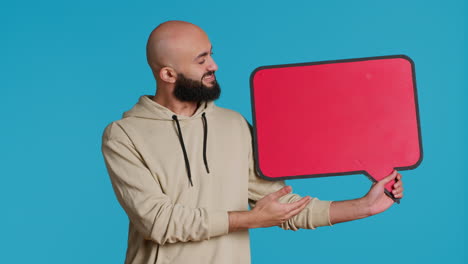 arab person holding red speech bubble icon in studio