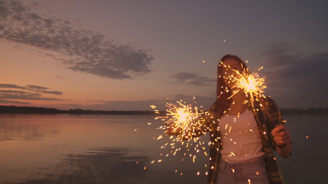 Dancing friends with fireworks have fun and celebrate the holiday together guys and girls in the summer on the beach. Sparklers in the hands of people having fun.