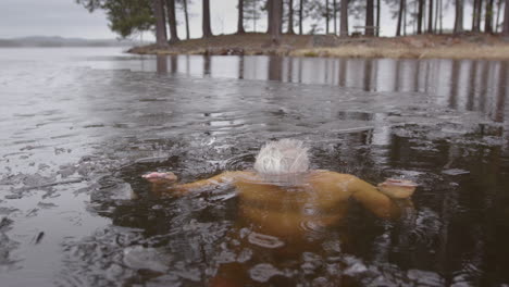 Toma-En-Cámara-Lenta-De-Un-Hombre-De-Unos-50-Años-Sumergiendo-La-Cabeza-Bajo-El-Agua-Helada-Del-Lago.