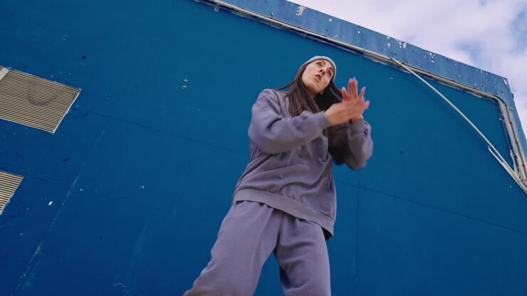 Donna in tuta da ginnastica che posa davanti a una parete blu