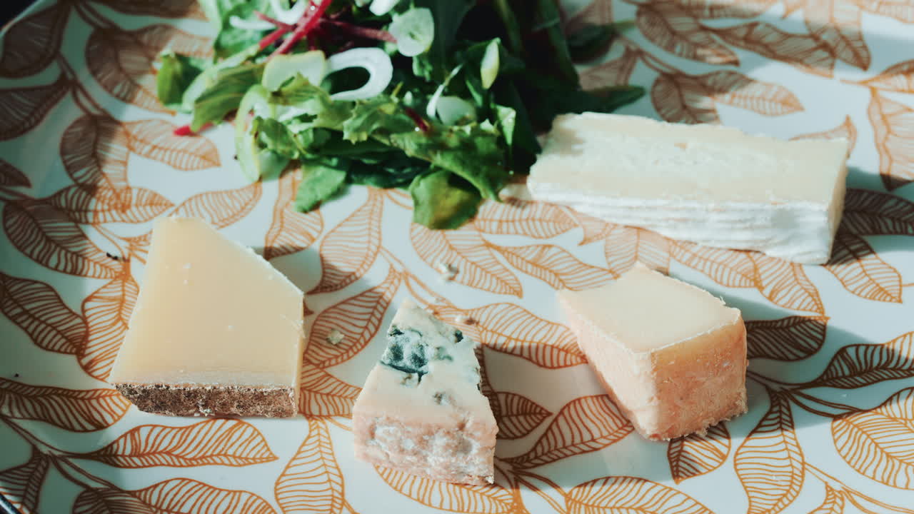 Close up of a fork and knife slicing into a piece of cheese from the platter