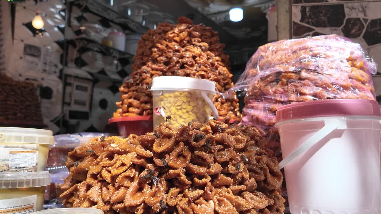 Bees are covering traditional sweets chebakia, sellou and briouates displayed at a market stall in Fes el Bali Medina, Morocco