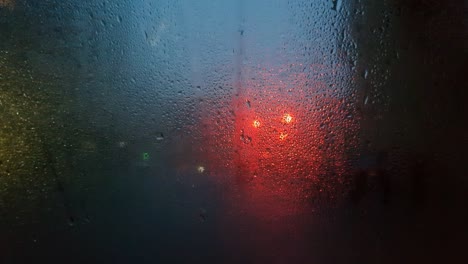 abstract red light of a traffic light through the wet misted glass of a car.
