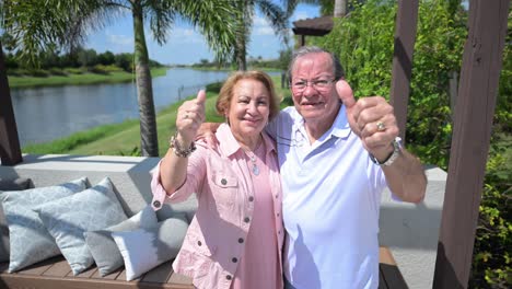 happy customers give a thumbs up sign outside in their new pool area in their luxury upscale home backyard