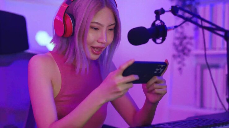 Giovane donna asiatica entusiasta che gioca a un gioco mobile e fa streaming