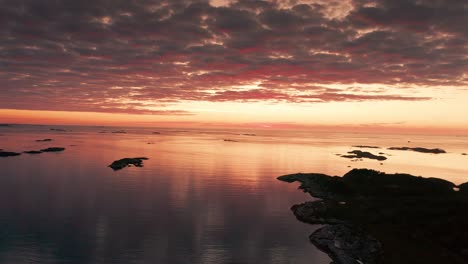 imágenes aéreas de una puesta de sol sobre un archipiélago costero, con las fuertes nubes tormentosas reflejadas en el mar tranquilo