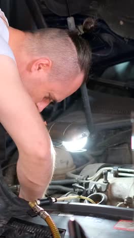 man working on car engine with a flashlight