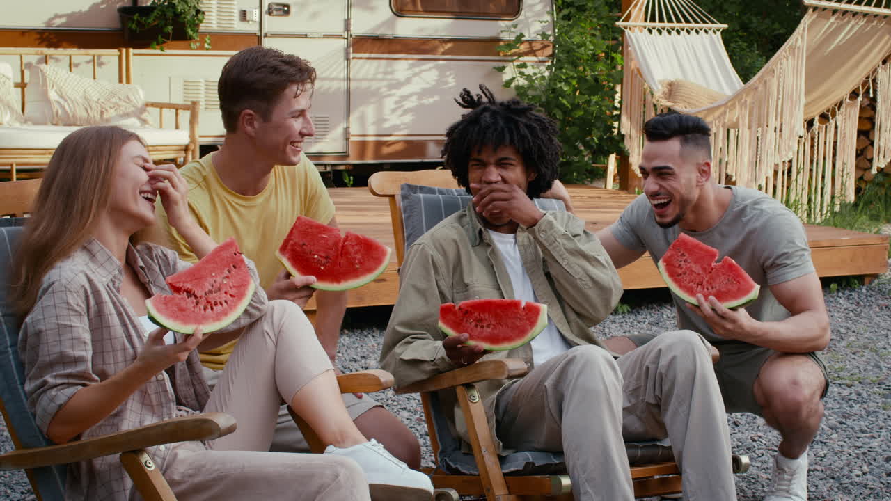 amigos disfrutando de la sandía en un campamento
