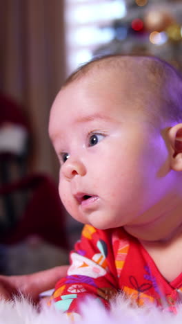 beautiful caucasian baby lies on the floor. little boy is trying to hold his head and mommy supports the child. vertical video
