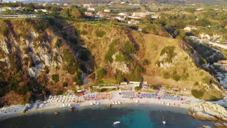 aerial view away from a beach at cabo vaticano, during golden hour, in calabria, south italy - pull back, drone shot