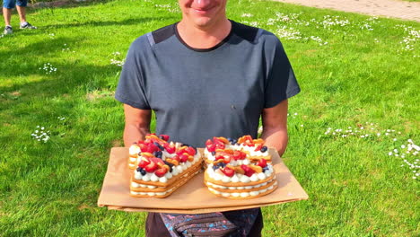 happy man holding cakes outdoors, motion view