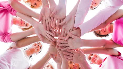 Diverse-group-of-smiling-women-touching-hands-outdoors-in-the-sun