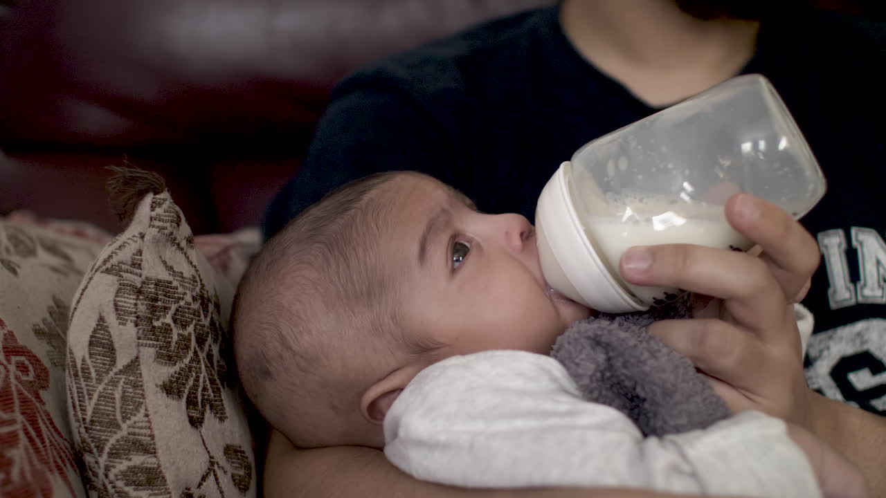 padre sosteniendo una botella de leche alimentando a su bebé de 2 meses