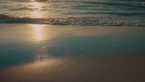 Waves-washing-up-on-beach-during-sunset,-slow-motion