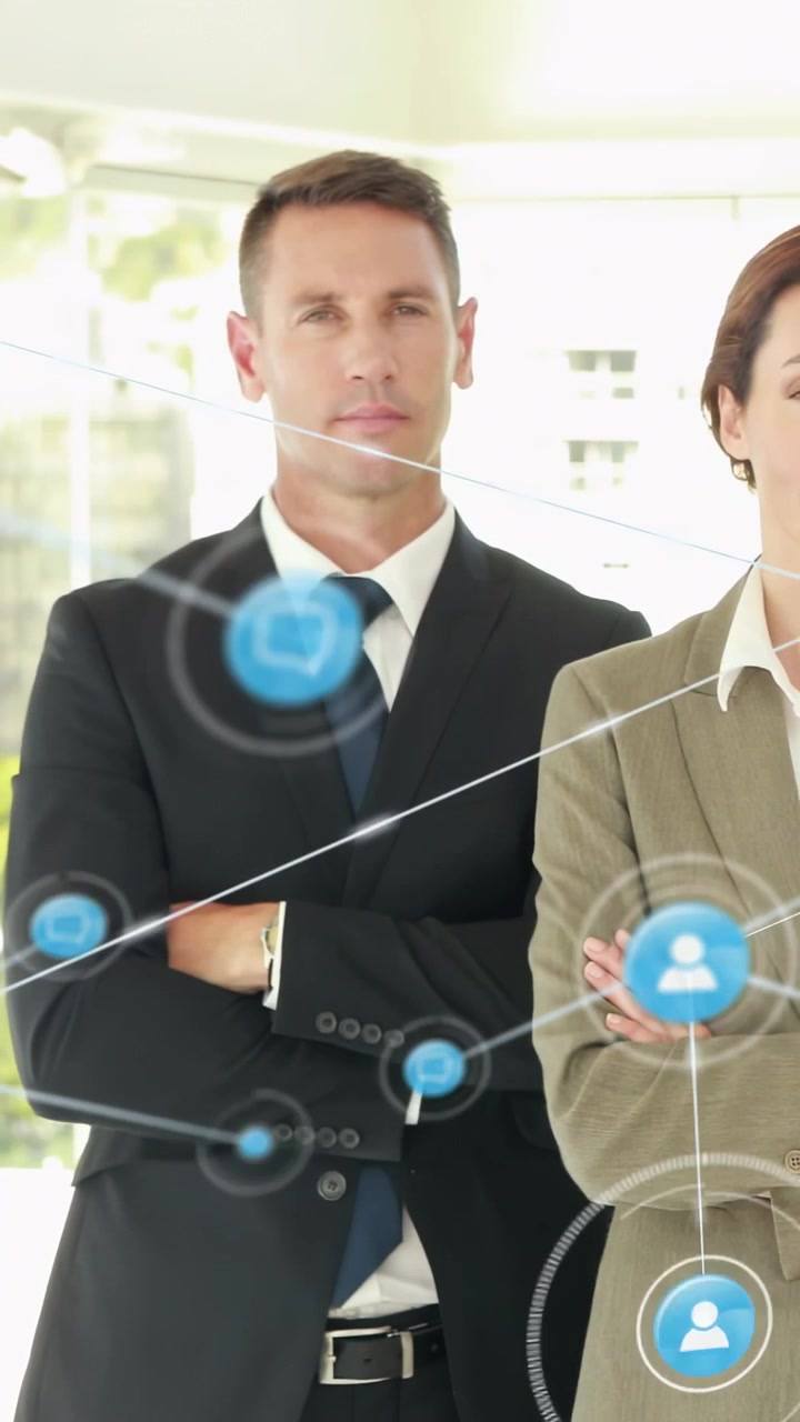 Vertical video: Two execs posing in business office as shot starting blue icons passing over them