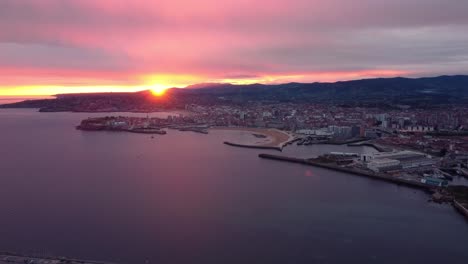 Imágenes-Aéreas-Del-Amanecer-De-La-Ciudad-De-Gijón-En-España,-Drones-Vuelan-Sobre-El-Puerto-Y-La-Playa