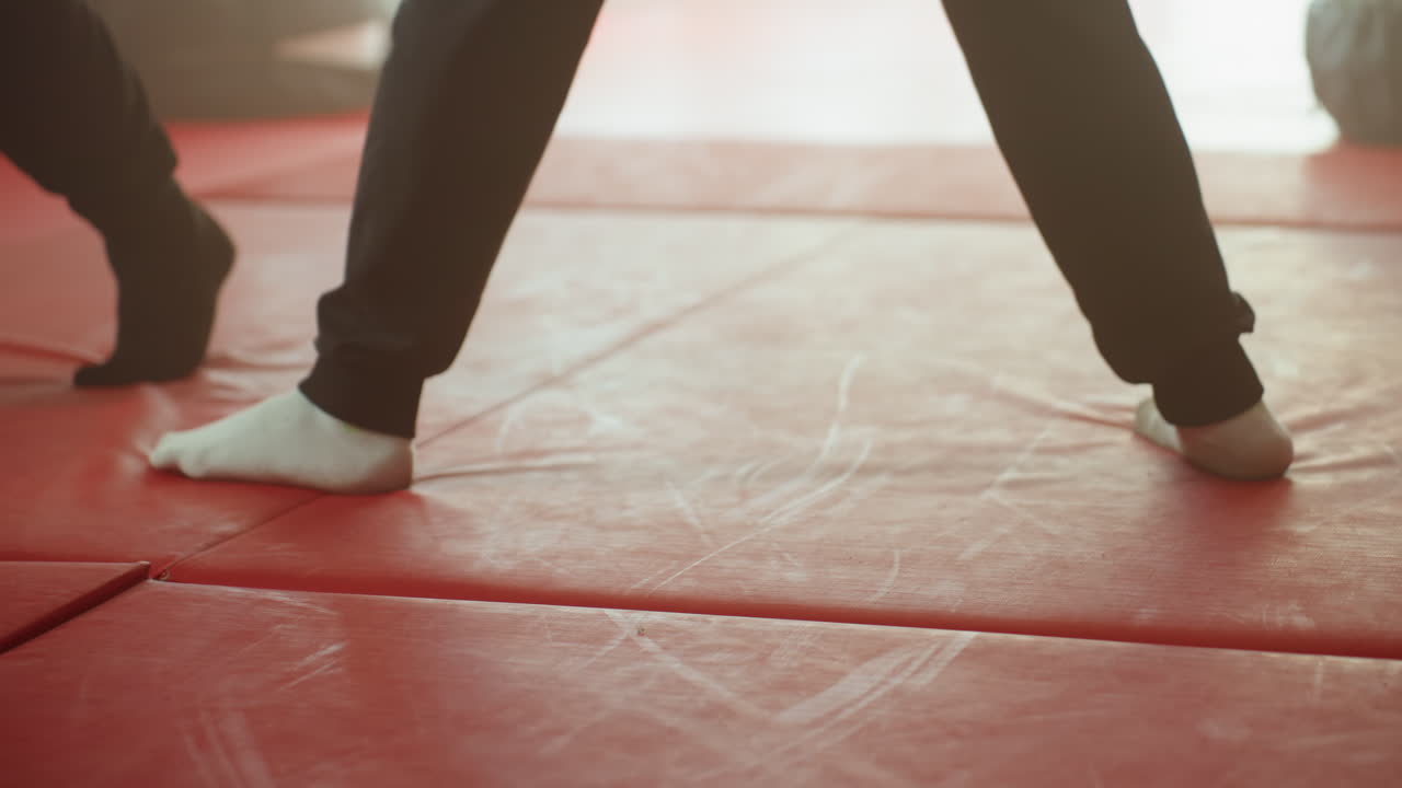 Boxer footwork with athletes wearing socks on red gym mat showing stance, posture, agility, and coordination during combat training emphasizing movement, precision, discipline, and physical control