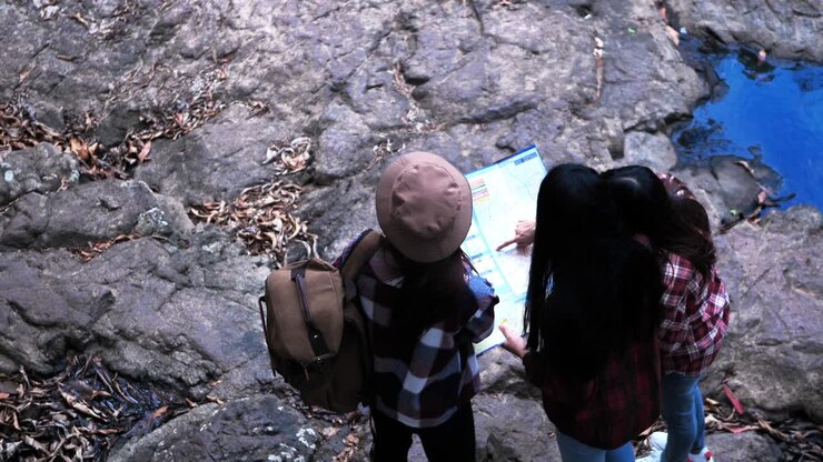 Grupos de amigas adolescentes asiáticas ayudándose mutuamente a encontrar direcciones de viaje con vista de mapa en el bosque. Vacaciones de aventura. Vista superior.