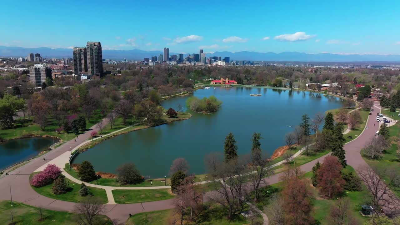Springtime summer tree wildflower blossom sunny blue sky City Park Downtown Denver Colorado aerial drone Ferril Duck Lake bike walking path green grass tall buildings forward high upwards motion