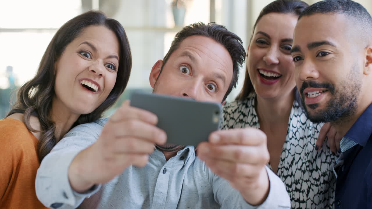 retrato de un feliz equipo de negocios multirracial tomando selfies después de reunirse en una oficina moderna