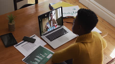 african american woman using laptop on video call with male colleague working from home