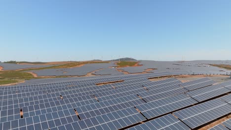 Aerial-wideview-of-sprawling-solar-panel-farm-across-hillside,-space-for-text