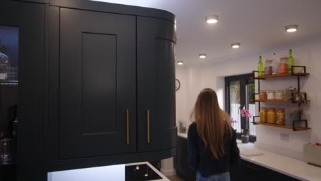 female-model-taking-wine-glass-from-a-corner-cupboard-in-a-modern-kitchen