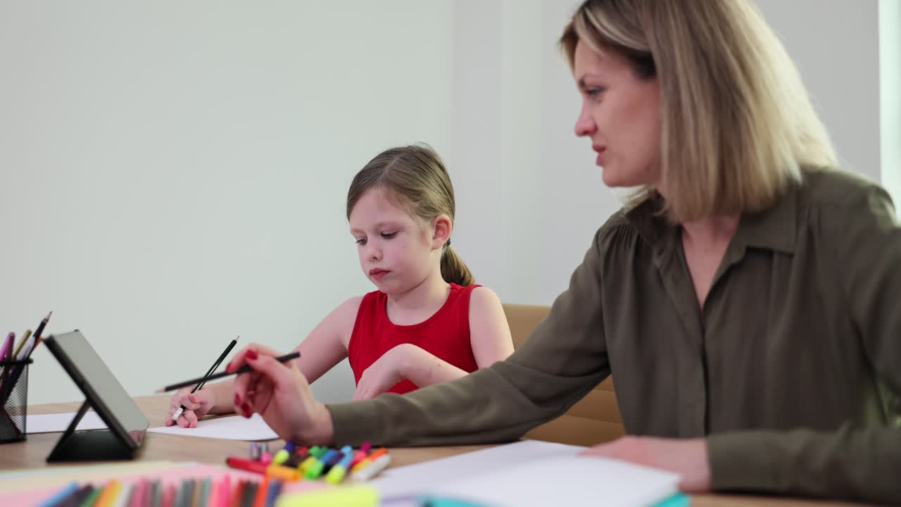 Adult and child drawing or studying together at a table