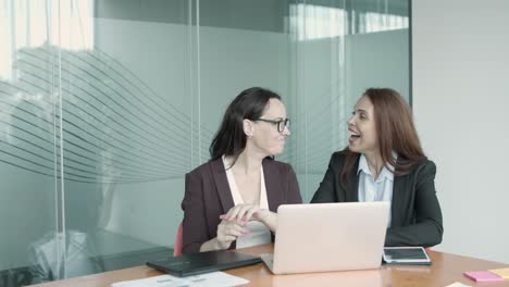 successful female colleagues talking, video chatting via laptop