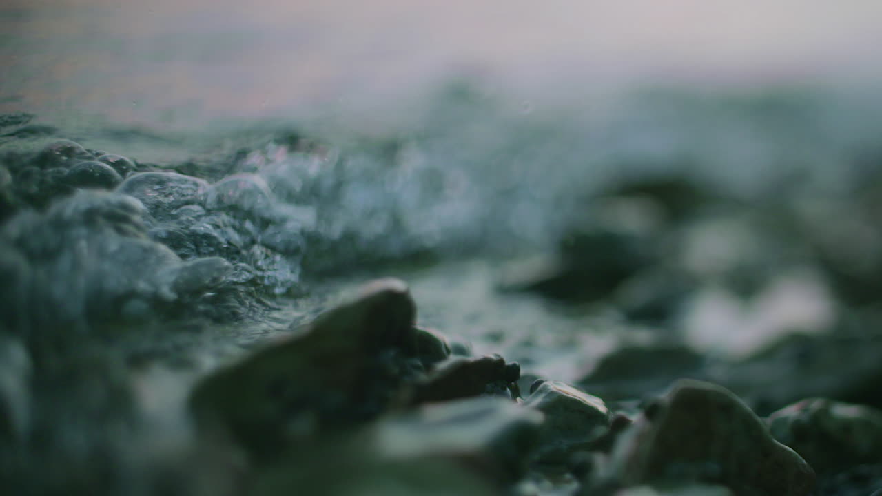 Primo piano di acqua serena che scorre sulle rocce con bolle