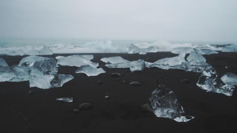 Kleine-Gezackte-Eisbrocken-Am-Diamond-Beach-In-Island,-Während-Die-Wellen-Brechen