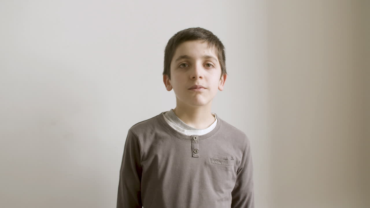 젊은 갈색 소년이 카메라를 보고 포즈를 취하고 있습니다.