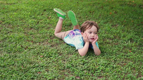 still shot of an isolated american bored child lying on the grass ground