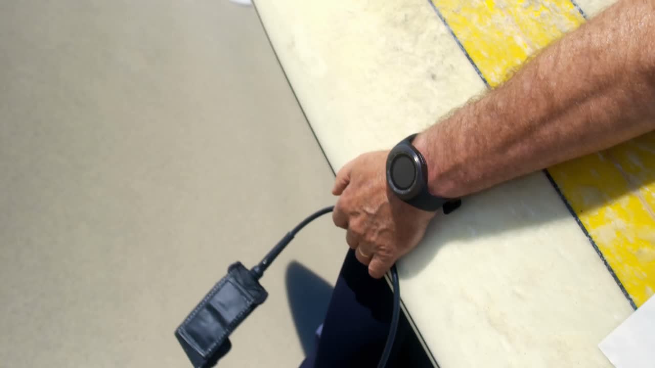 sección media de un surfista masculino caminando con una tabla de surf en la playa 4k