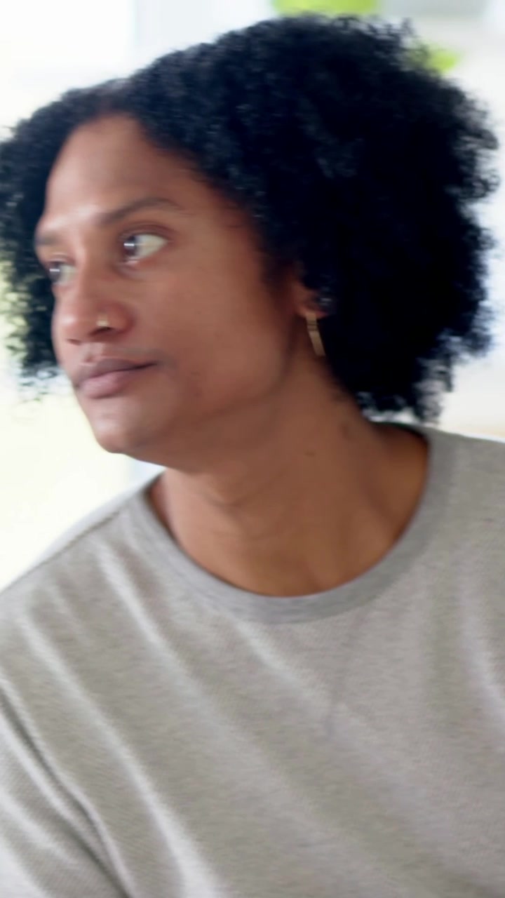 Vertical video: Sipping man in gray tee lifting green mug at home hearing voice turning, copy space