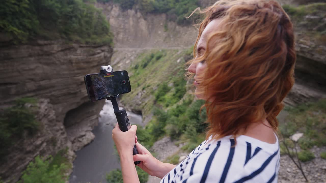 Woman recording video of a mountain canyon landscape