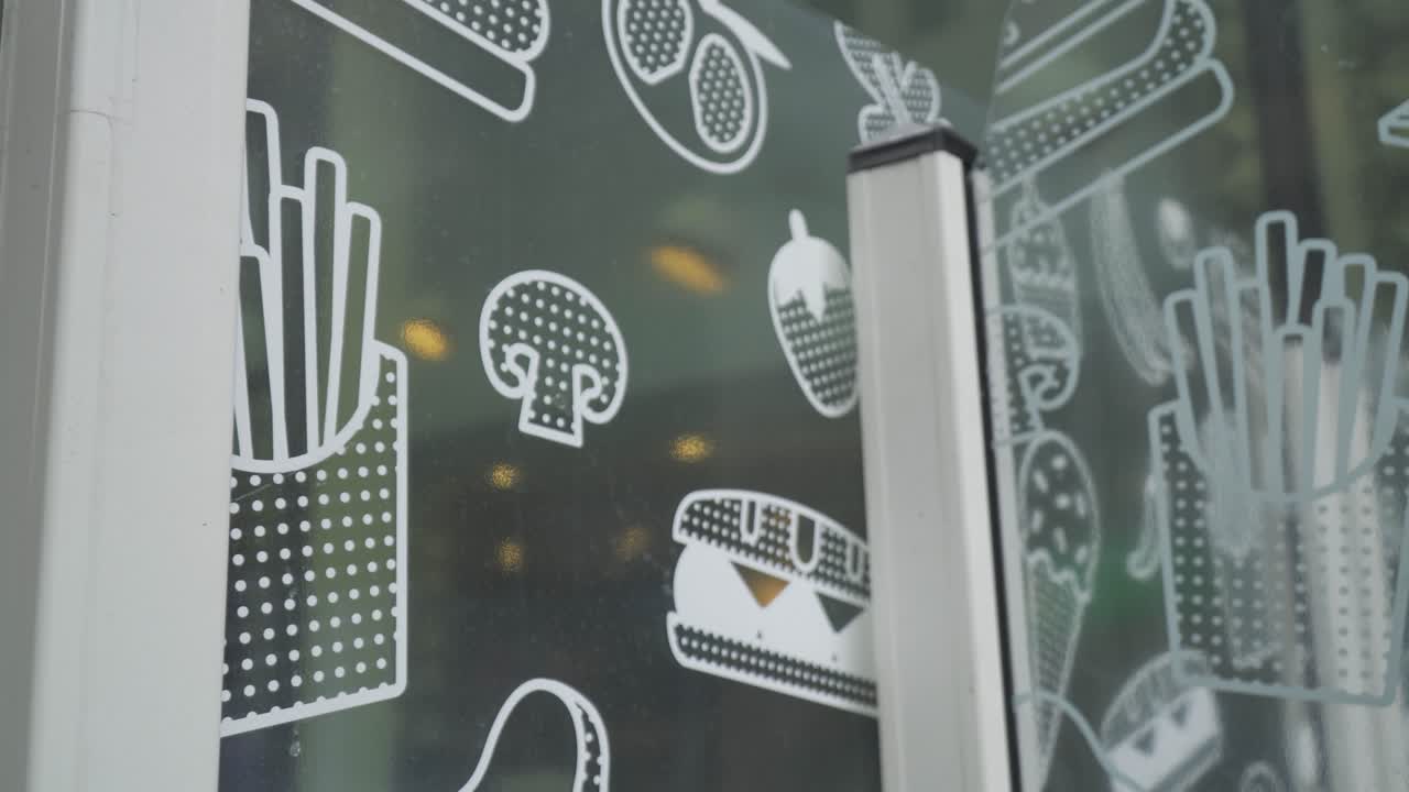 close up of glass wall outside of a restaurant with images of fruit burger ice cream chips and more nobody around slider movement shot
