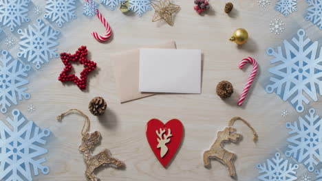 animation of christmas decorations with card and copy space over snowflakes on grey background