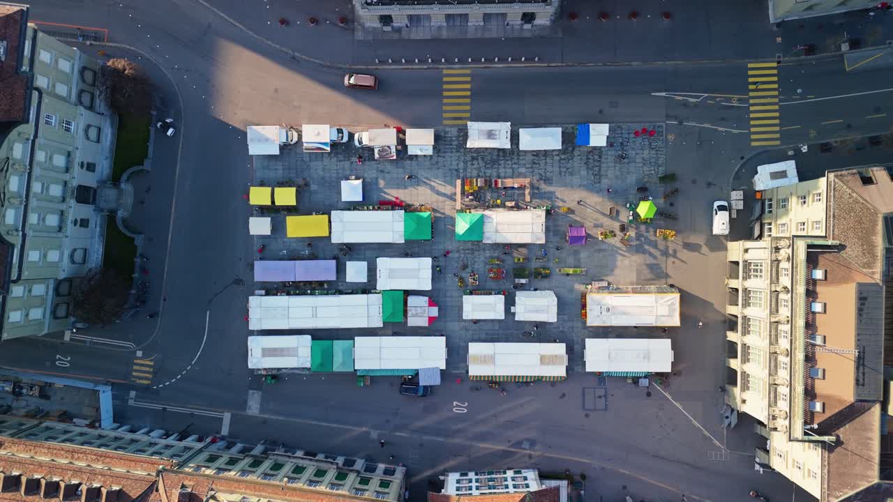 Birdview droneshot of the federalplace in Bern in front of the "Bundeshaus" where a market is happening during carneval