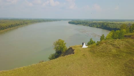 newly-wedded-couple-on-steep-riverbank-bird-eye-view