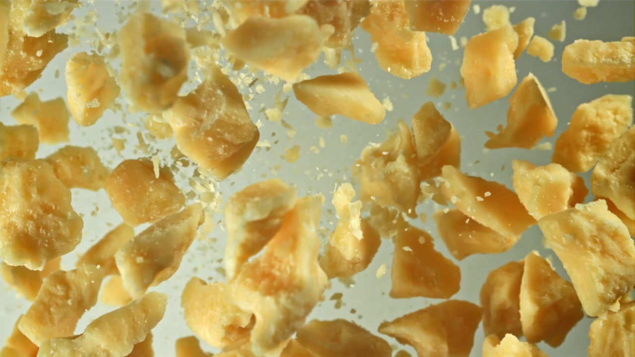 Pezzi di formaggio Parmigiano che cadono al rallentatore