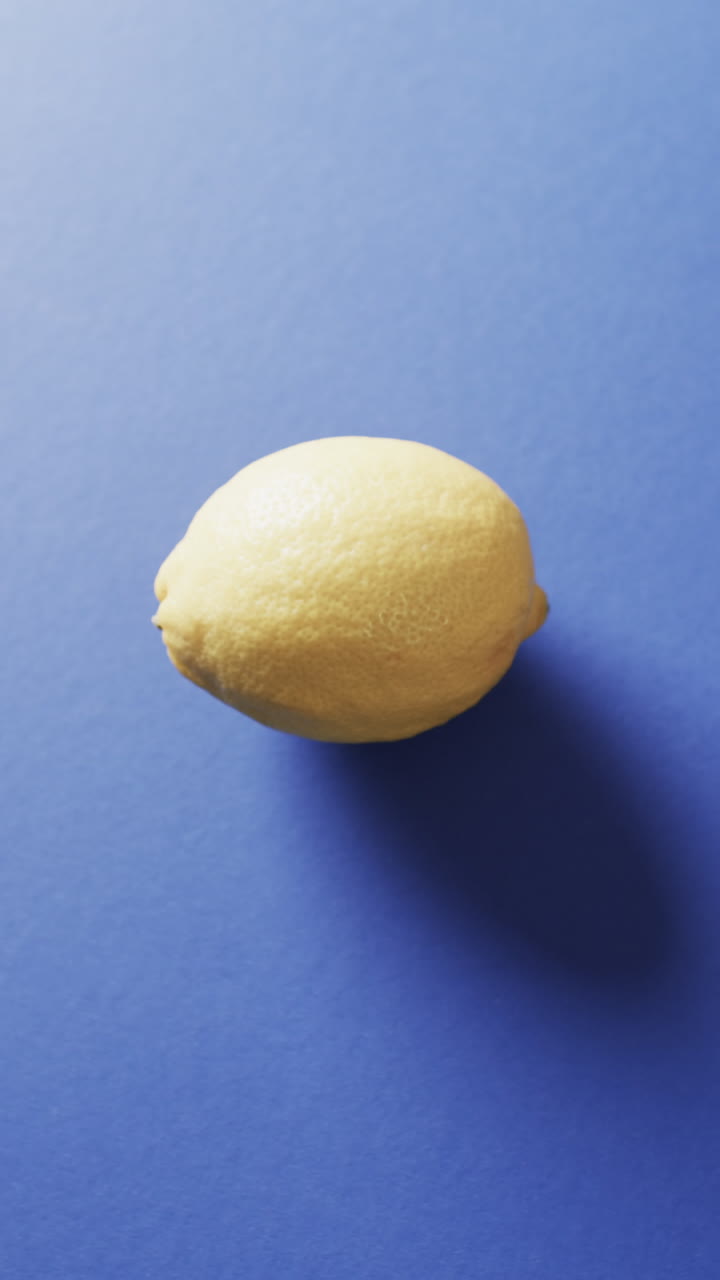 Vertical video of lemon with copy space on blue background