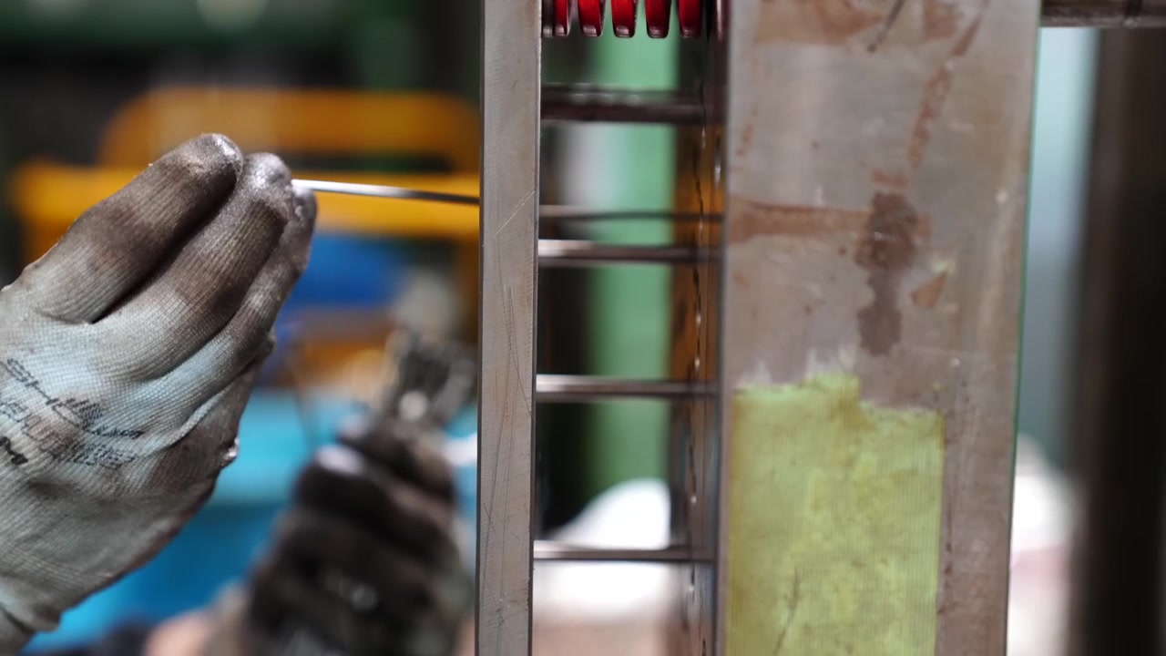 Worker adjusting a metal injection mold with red ejector pins during eraser manufacturing in Japan