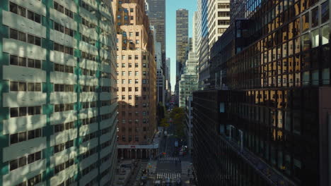 Forwards-fly-above-street-between-modern-high-rise-buildings-with-colour-facades.-Manhattan,-New-York-City,-USA
